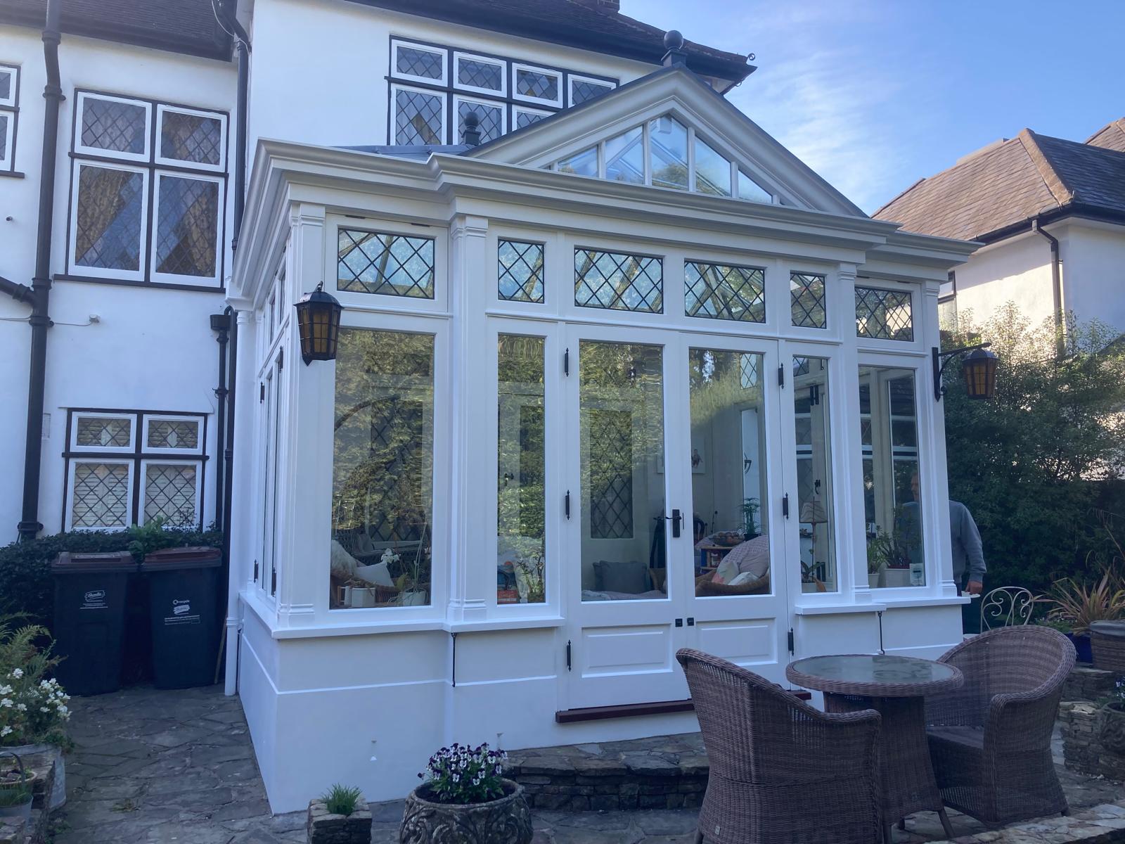 Period orangery with a decorative pediment gable, leaded glass windows and white woodwork