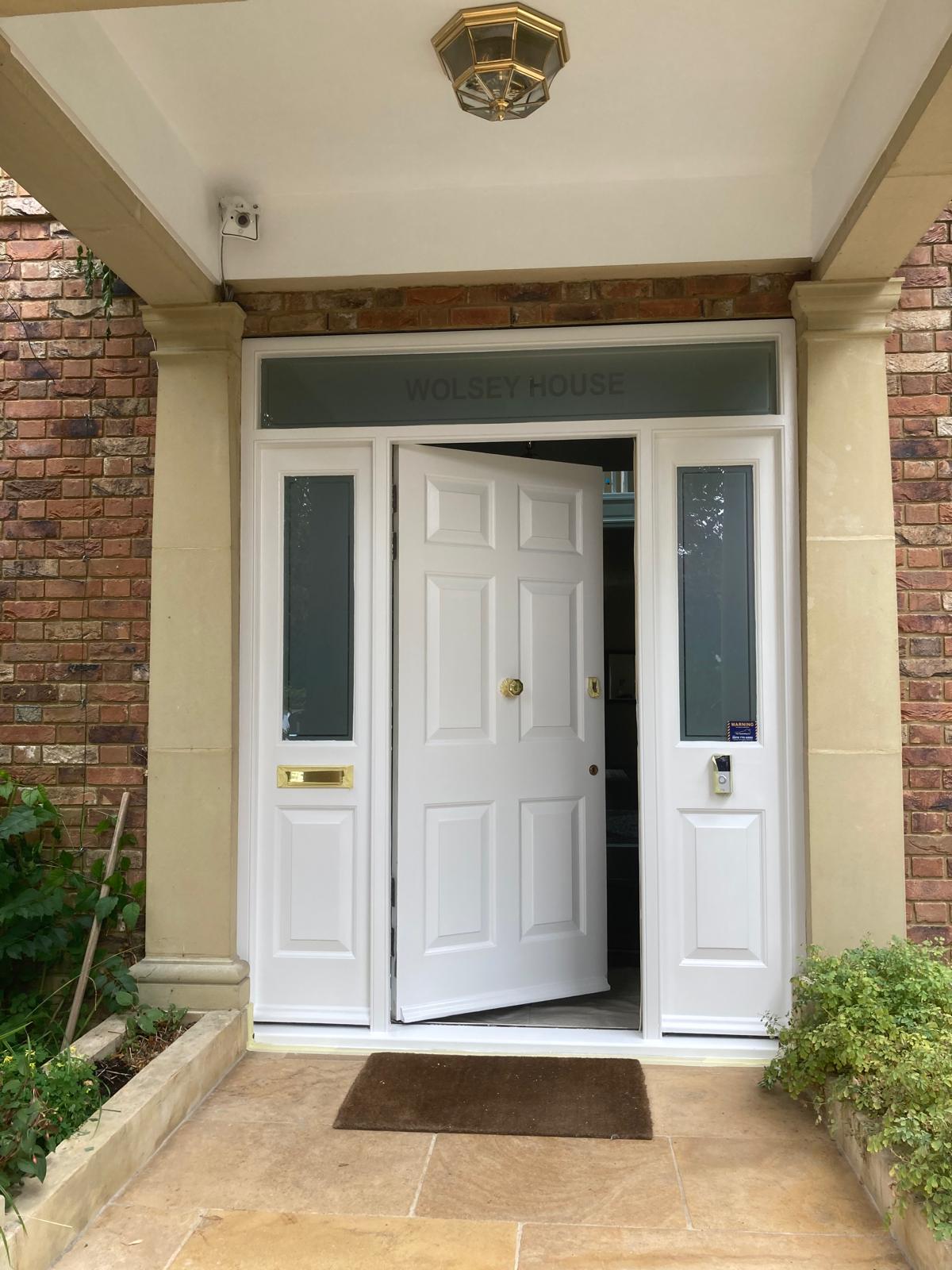 White-painted front door with sidelights and a fanlight inside a sandstone portico