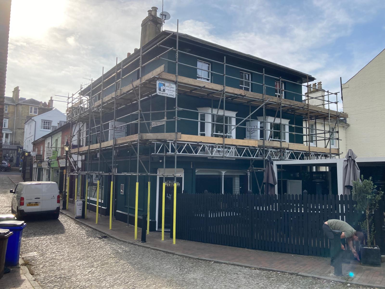 Freshly painted deep green restaurant facade with crisp white sash windows on a cobbled street corner